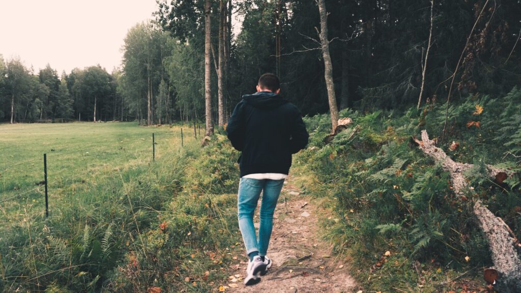 Imagen actual: woman in black jacket and blue denim jeans walking on green grass field during daytime